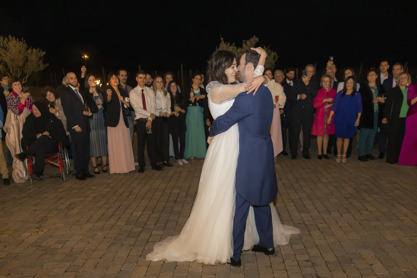 Primer baile de los novios al aire libre rodeados de invitados
