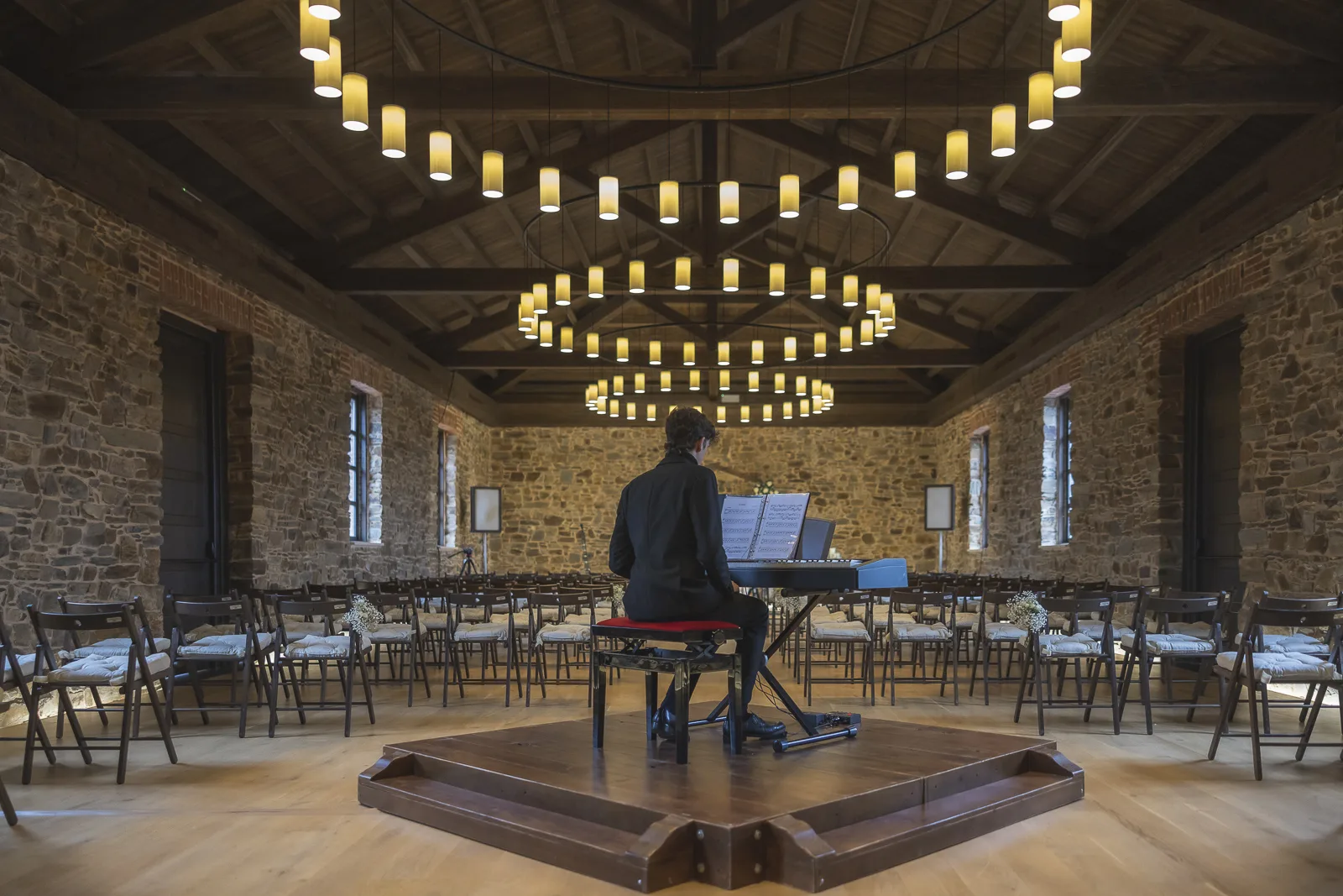 El salón de piedra de Finca Valdemora con sus lámparas y el piano preparado para la ceremonia
