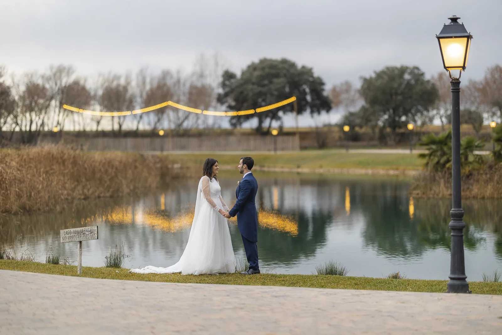 Los novios junto al lago al anochecer, con las farolas encendidas
