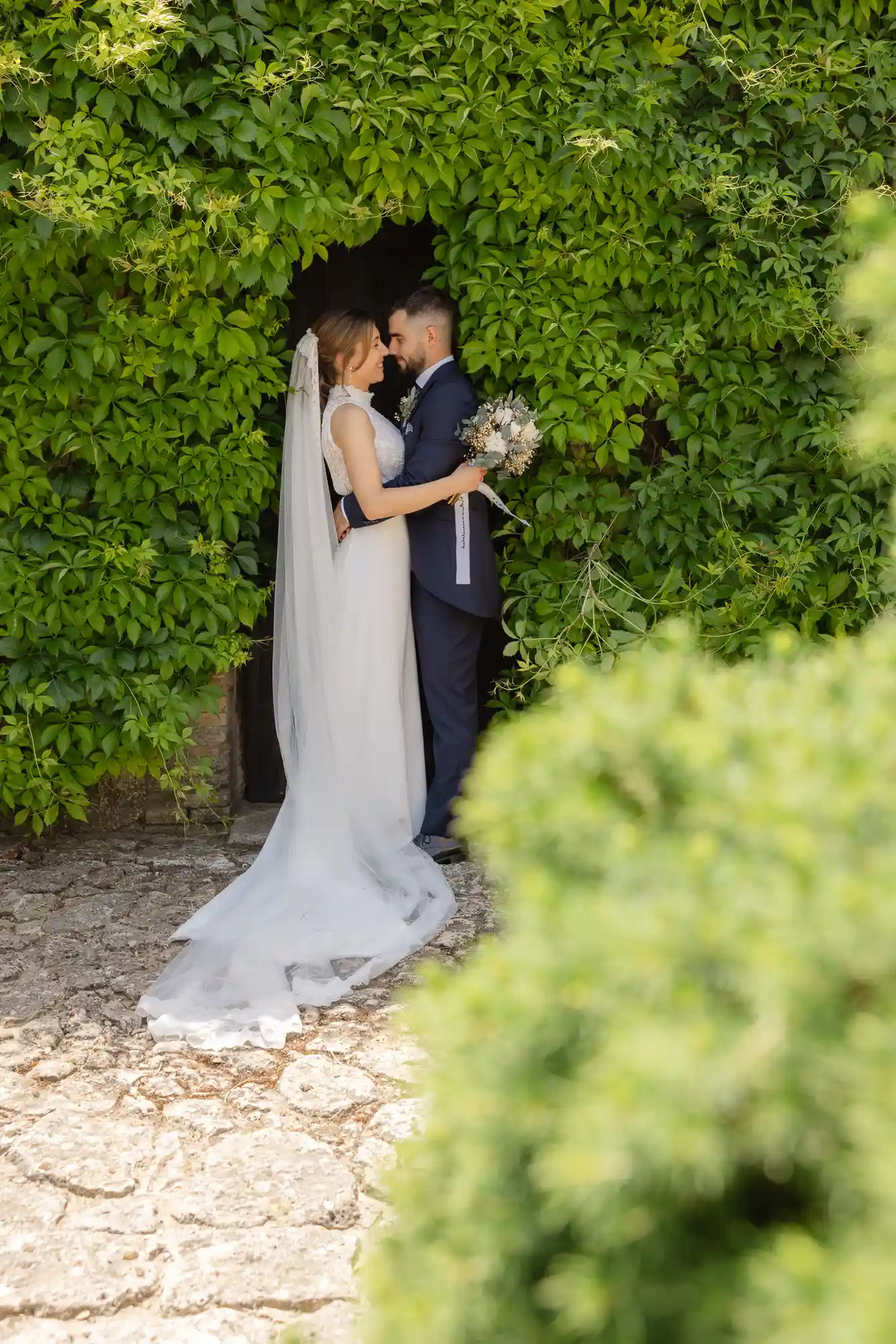 Novios en una puerta cubierta de hiedra en Bodegas Arzuaga