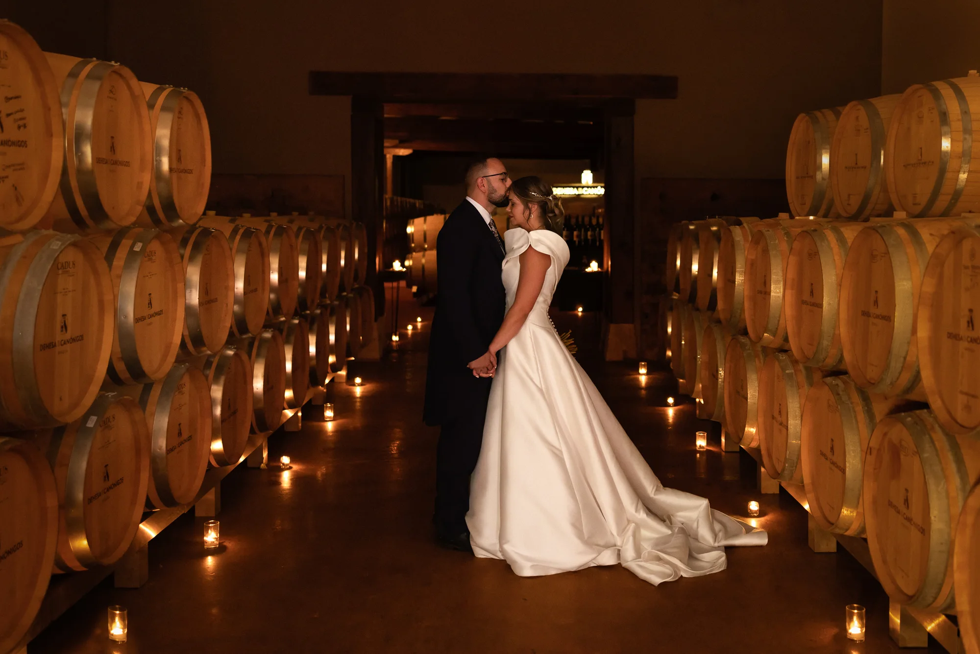 Fotógrafos de boda en Ribera del Duero: novios entre las barricas iluminadas con velas en Dehesa de los Canónigos, Pesquera de Duero