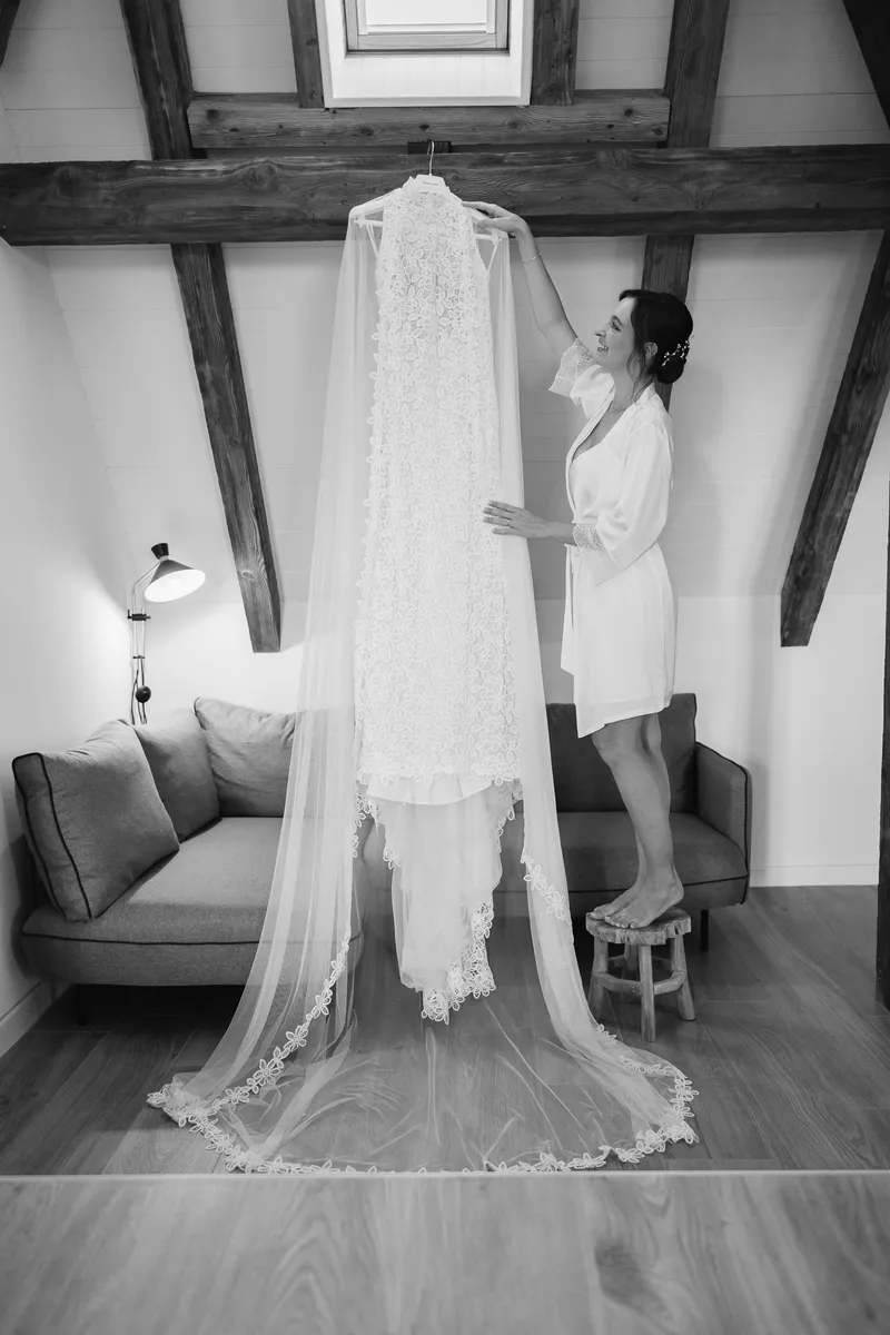 Vestido de novia colgado bajo las vigas de madera de la casa de Les Jardins de Madeleine