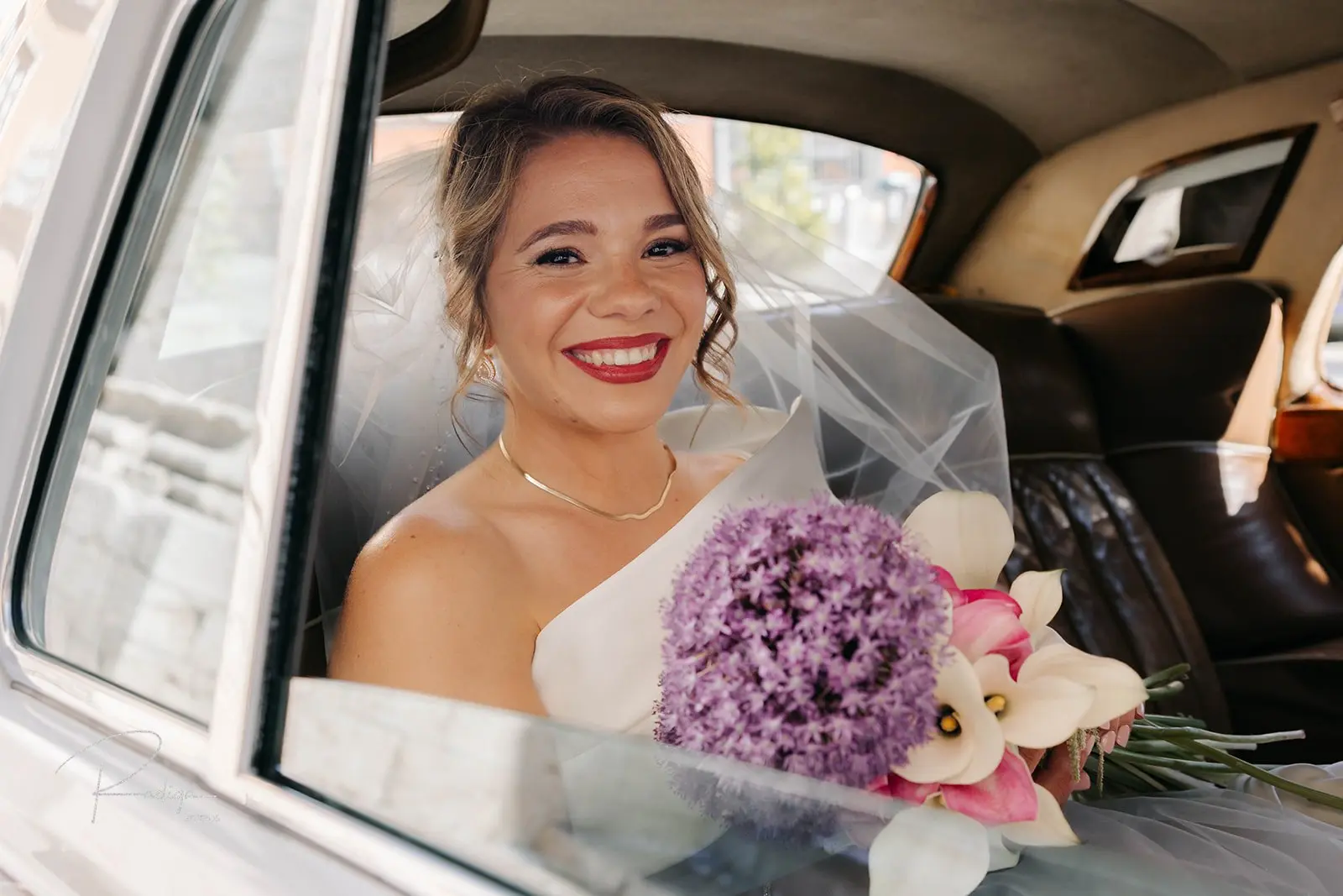 La novia sonríe dentro del coche clásico camino de la iglesia