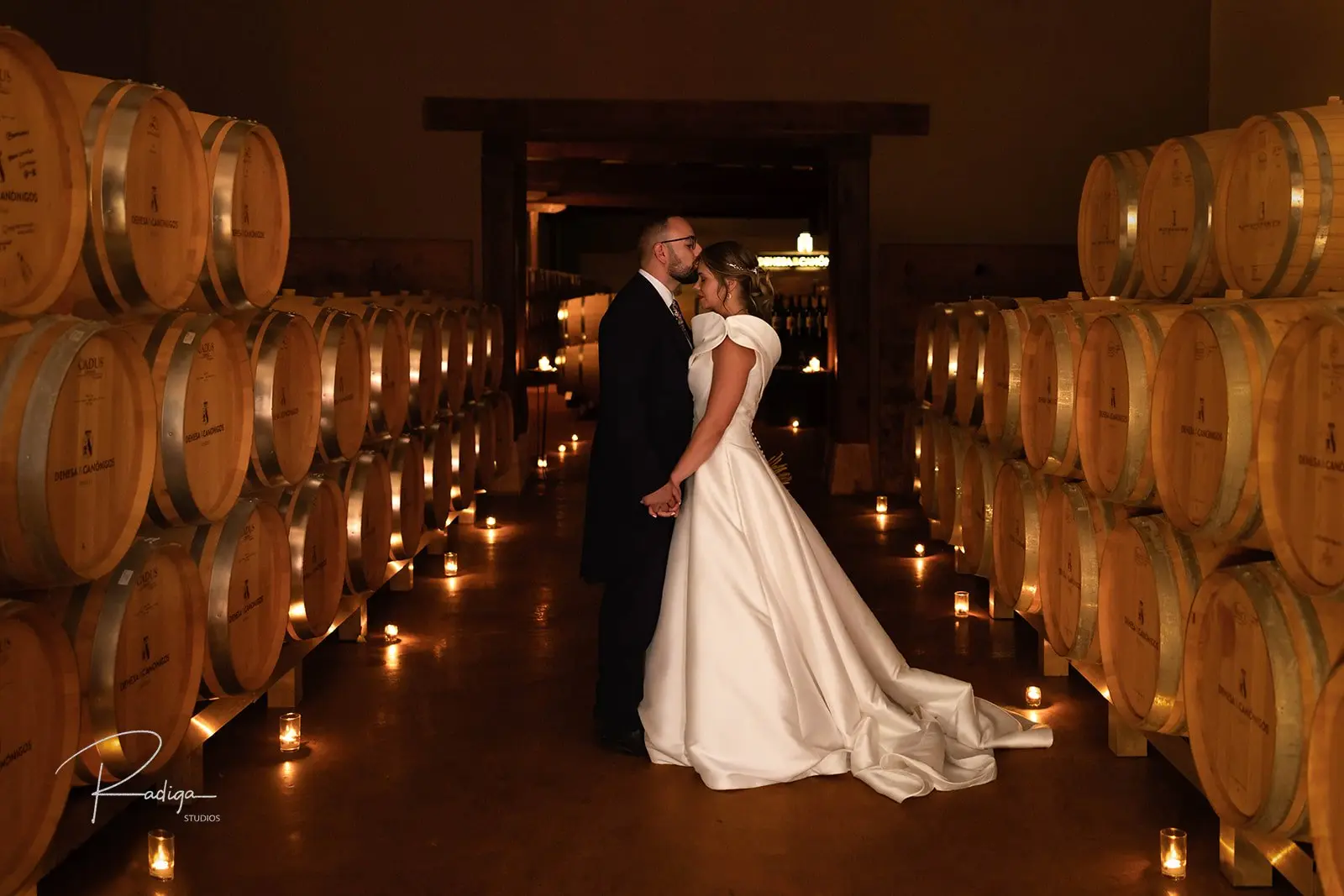 Los novios en la sala de barricas de Dehesa de los Canónigos iluminada con velas