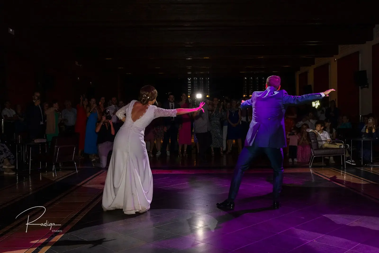 Los novios bailan en la pista iluminada rodeados de invitados