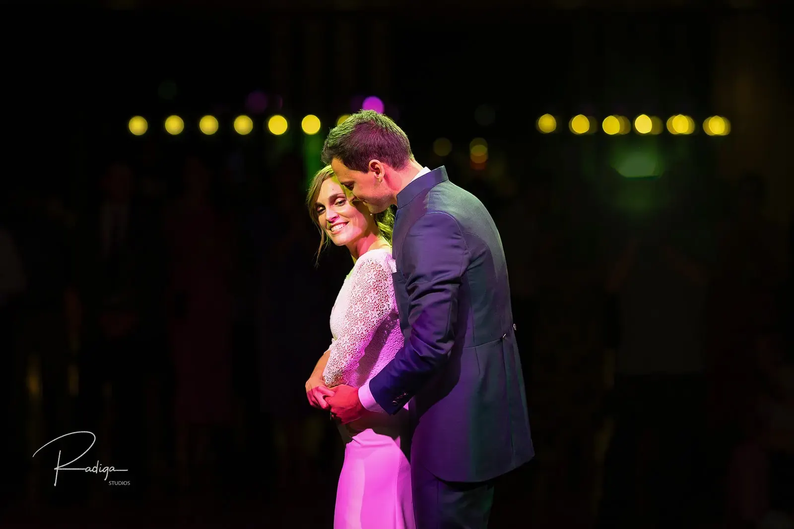 Los novios abrazados en la pista con luces de colores