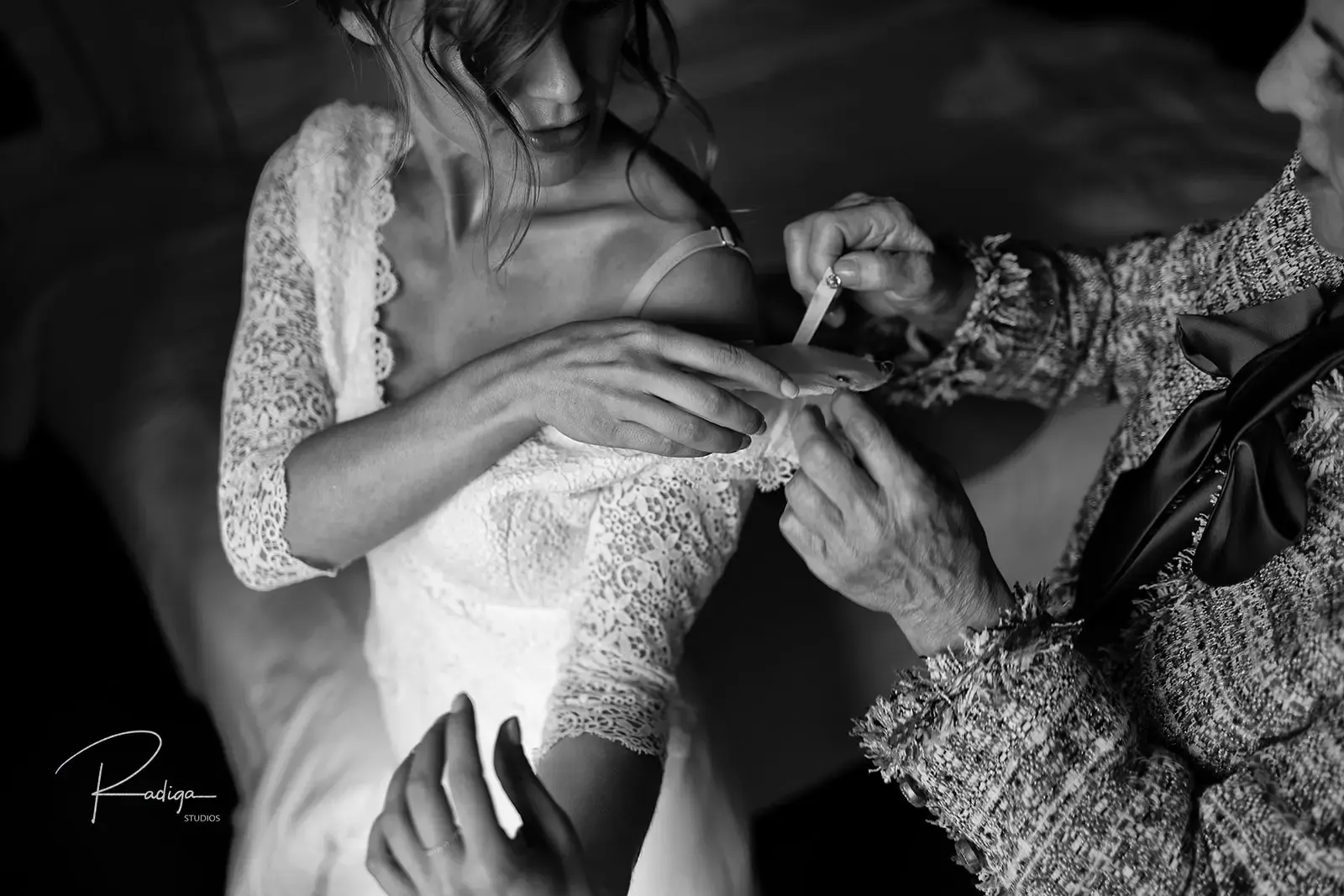 Abrochan los botones del vestido de encaje de la novia, en blanco y negro