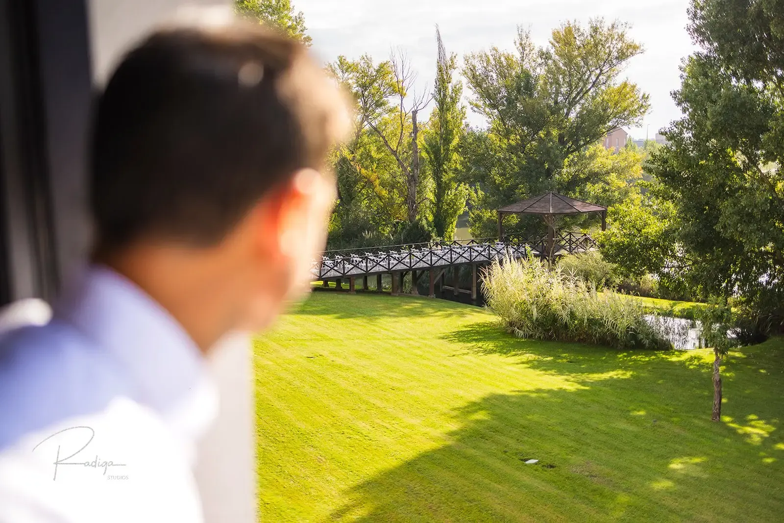 El novio mira por la ventana hacia los jardines del palacio