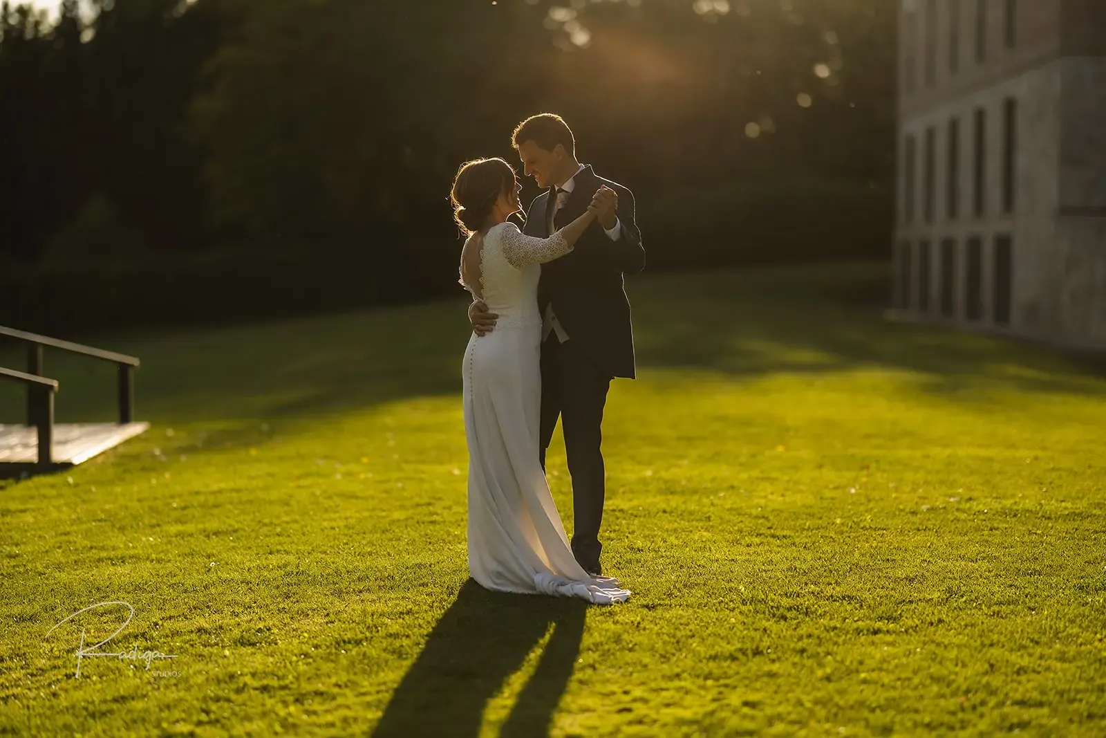 Los novios abrazados en el césped con el sol del atardecer