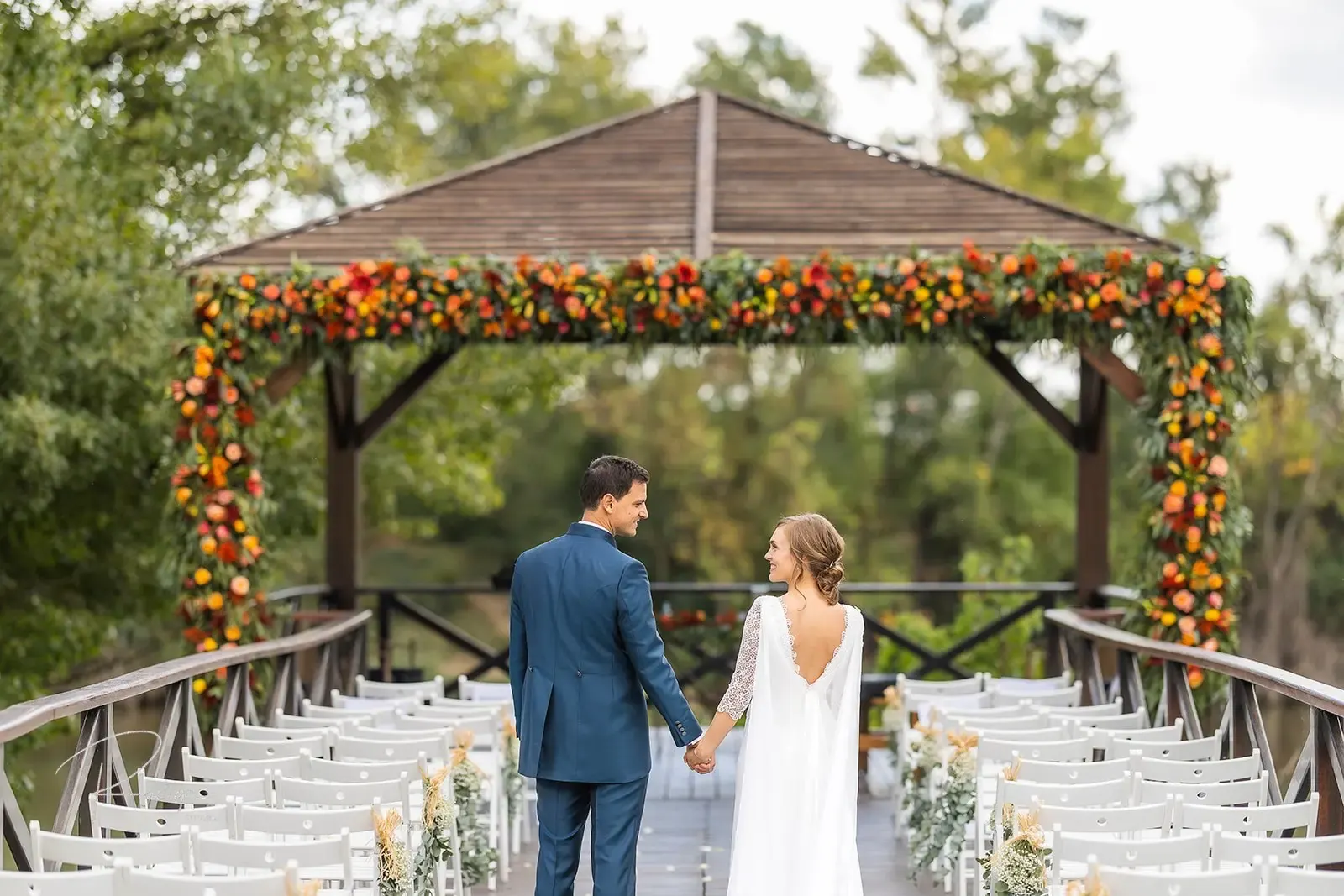 Los novios bajo la pérgola del embarcadero decorada con flores de otoño