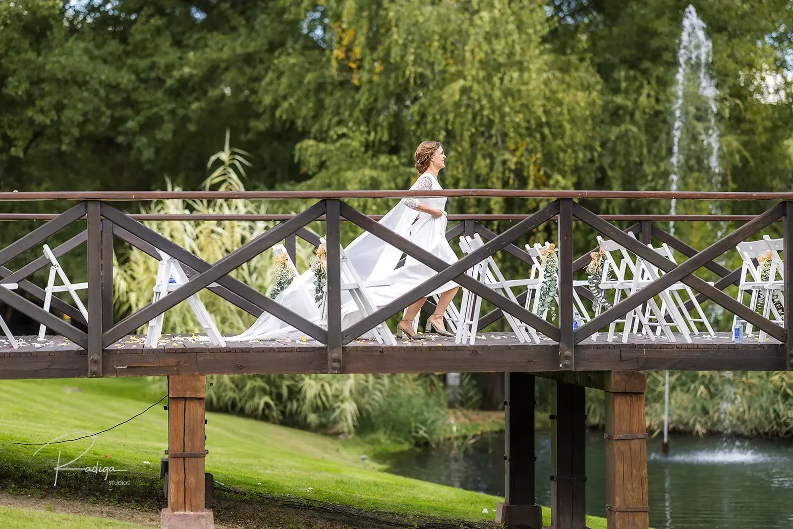 La novia en el puente de madera junto a la fuente del jardín