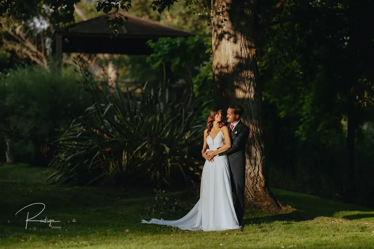 Los novios bajo una pérgola del jardín rodeados de vegetación