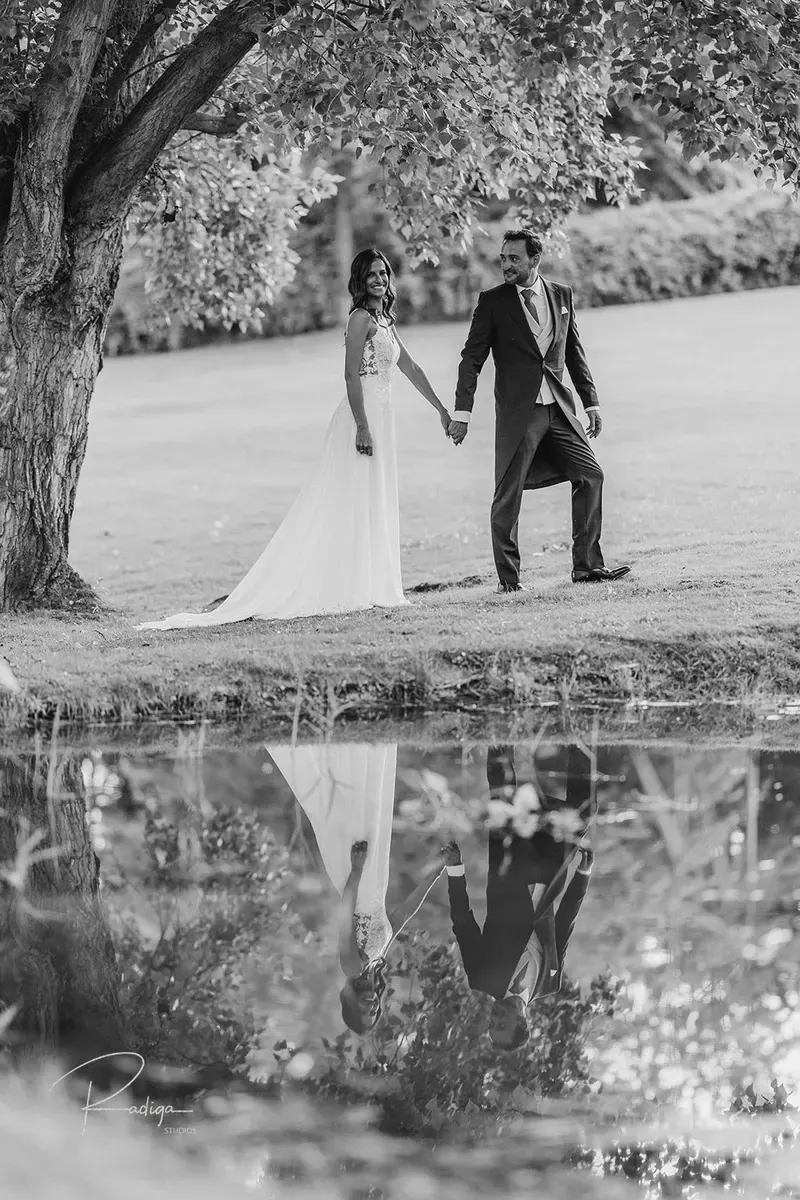 Los novios reflejados en el agua junto al embarcadero, en blanco y negro