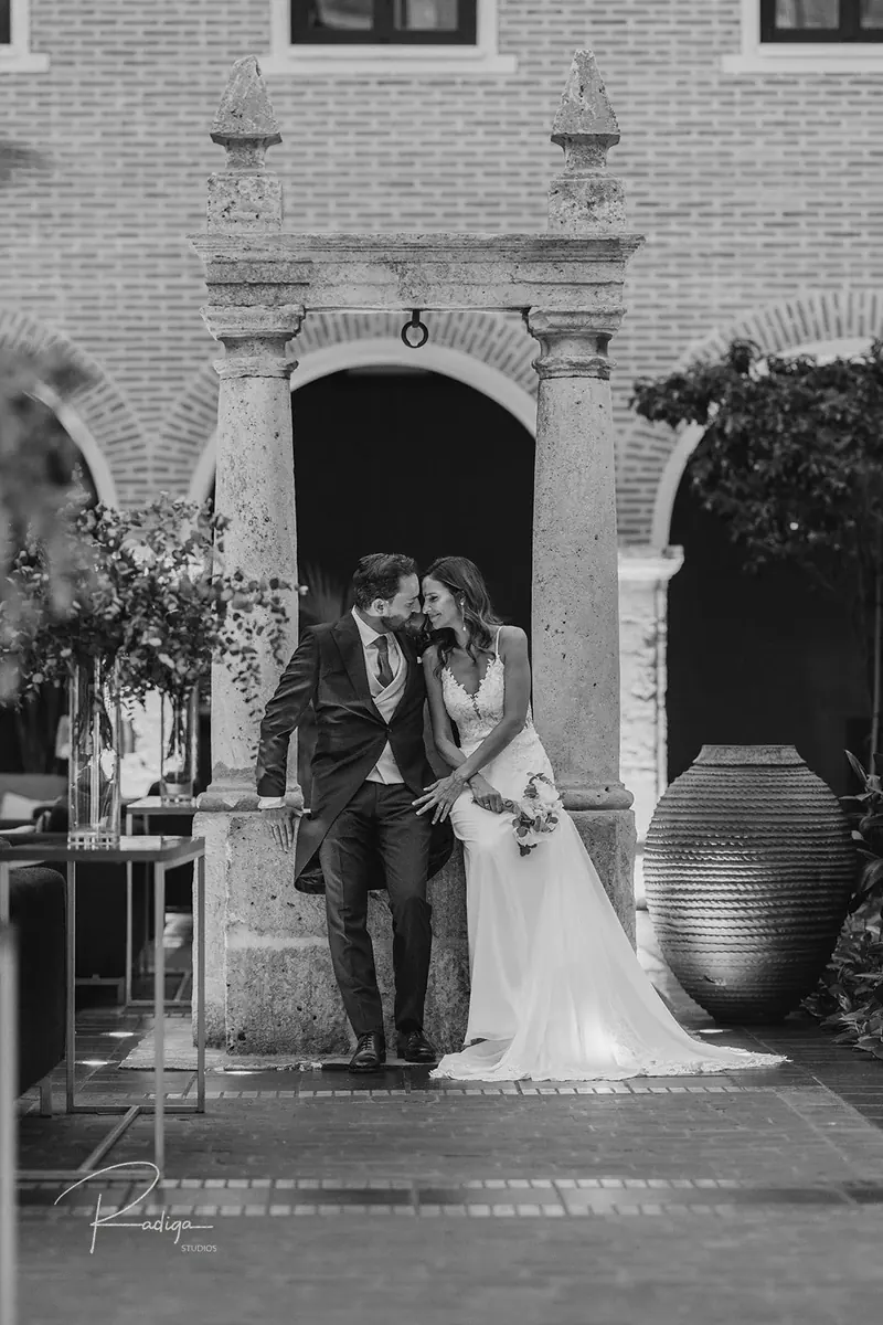 Los novios bajo un arco de piedra del claustro, en blanco y negro