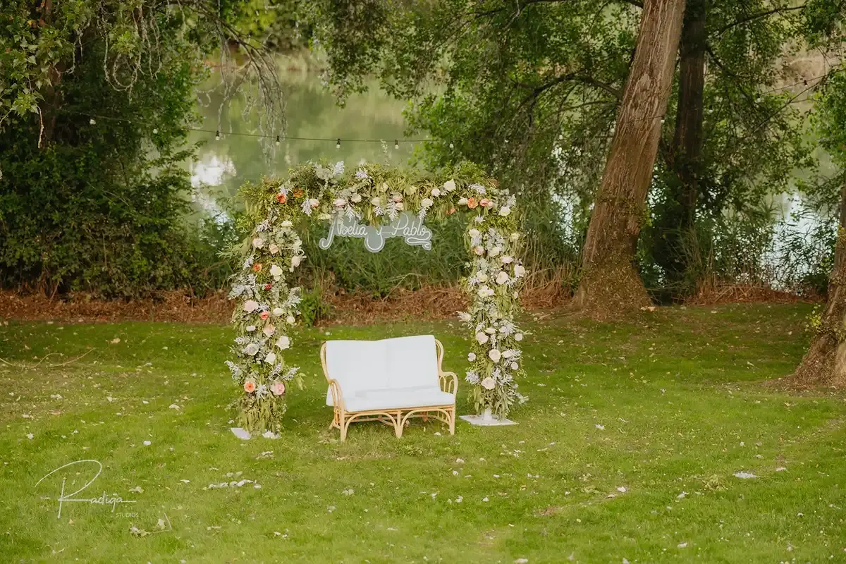 El arco de flores y el sofá blanco preparados en el jardín
