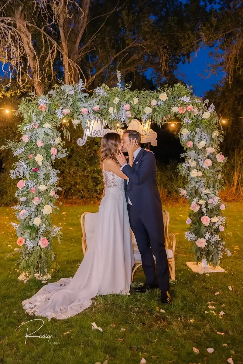 Los novios bajo el arco de flores iluminado por la noche