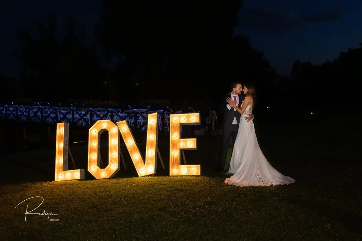 Los novios junto a las letras luminosas LOVE por la noche