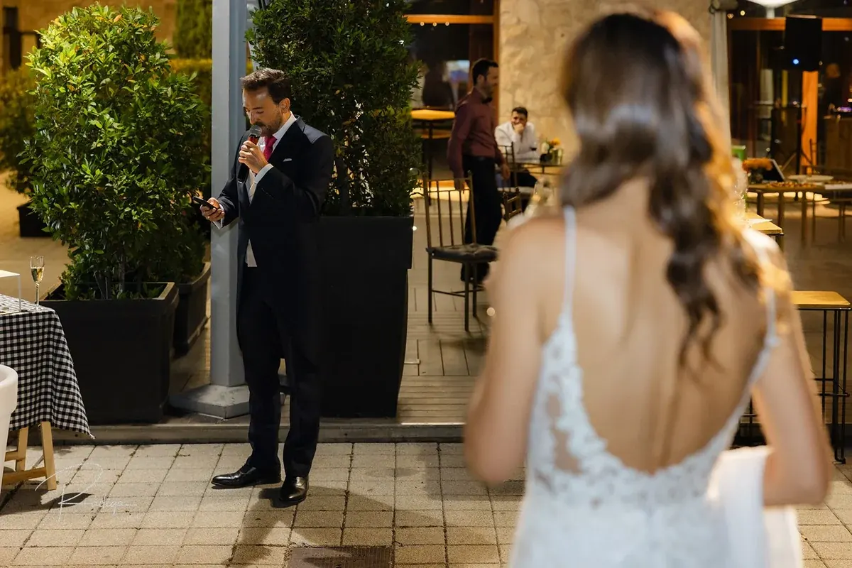 La novia de espaldas en la terraza con el novio al fondo