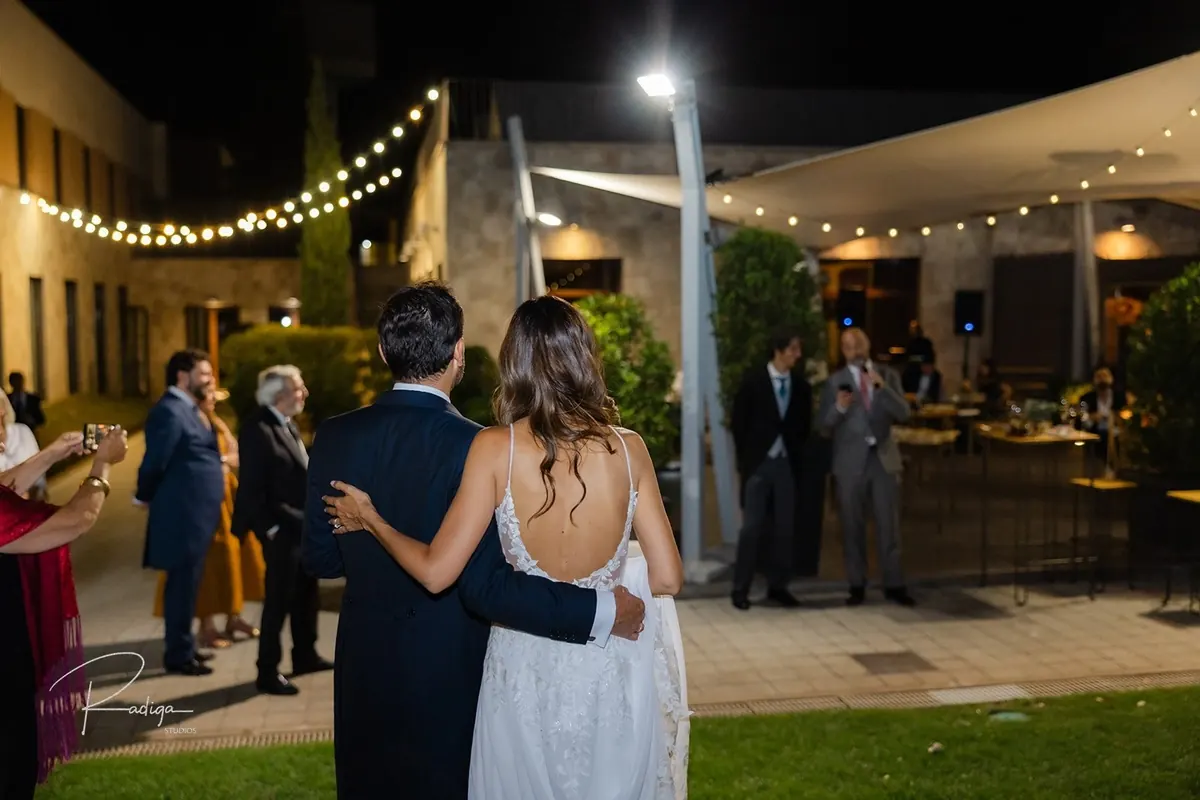 Los novios abrazados bajo las guirnaldas de luces de la terraza