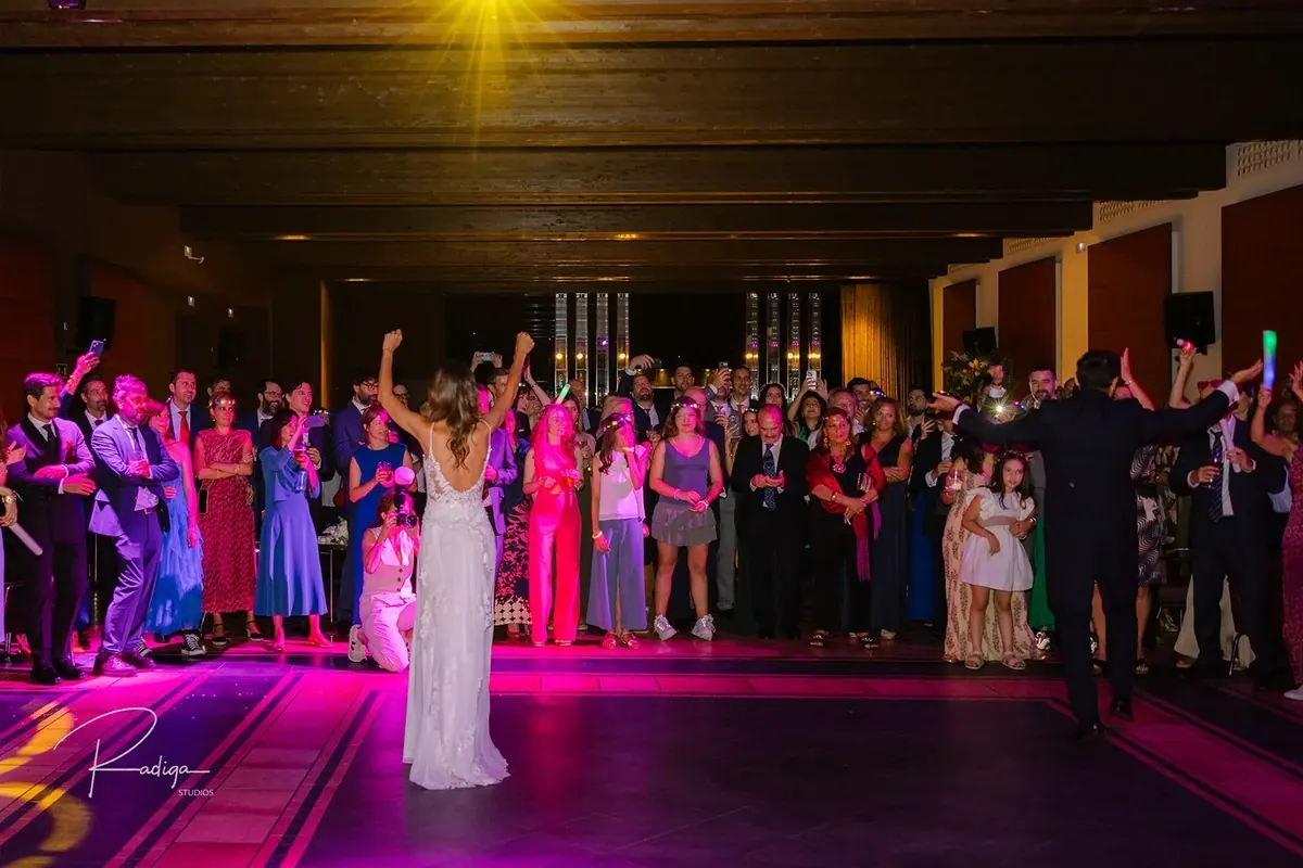 La novia levanta los brazos en la pista iluminada de colores