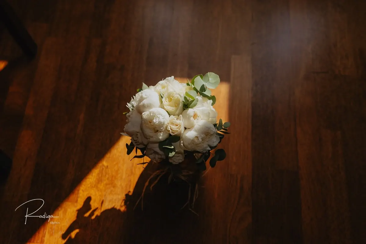 El ramo de rosas blancas sobre el suelo de madera iluminado por el sol