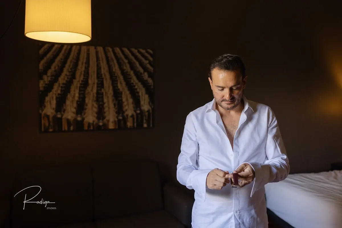 El novio se coloca los gemelos en la habitación del hotel