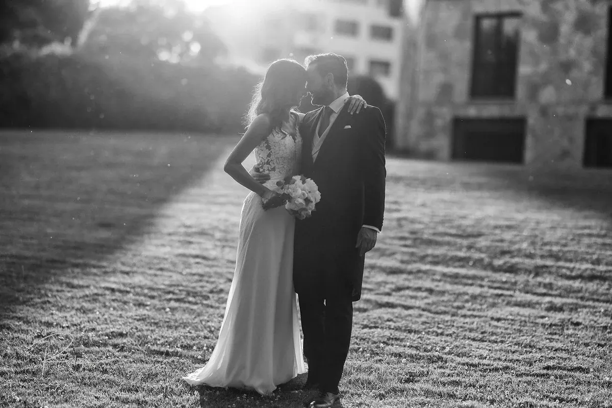 Los novios abrazados a contraluz en el jardín, en blanco y negro