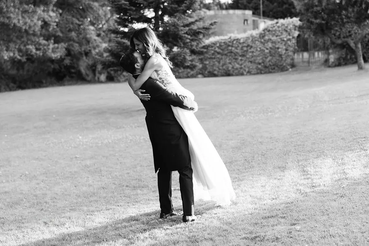 El novio levanta a la novia en el jardín, en blanco y negro
