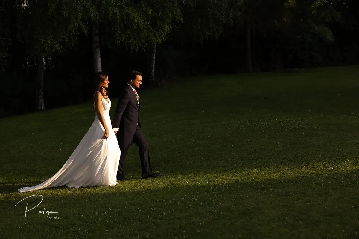 Los novios pasean por el césped con la última luz de la tarde