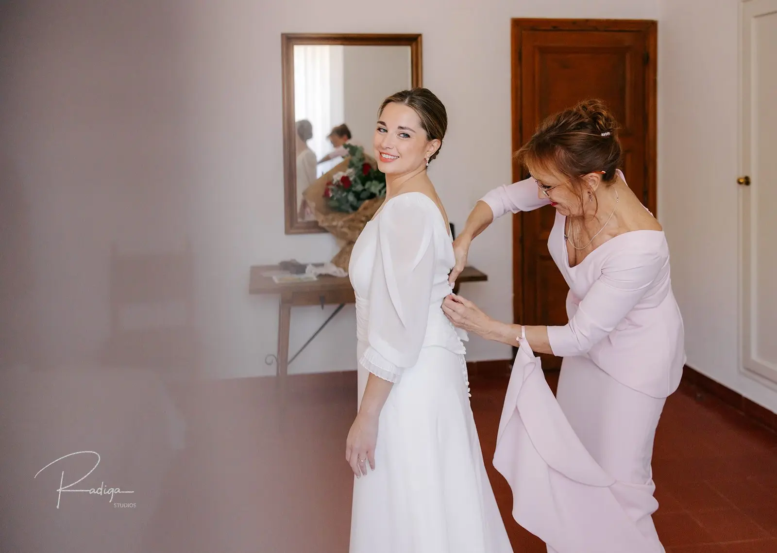 La madre ayuda a la novia a vestirse en su habitación del monasterio