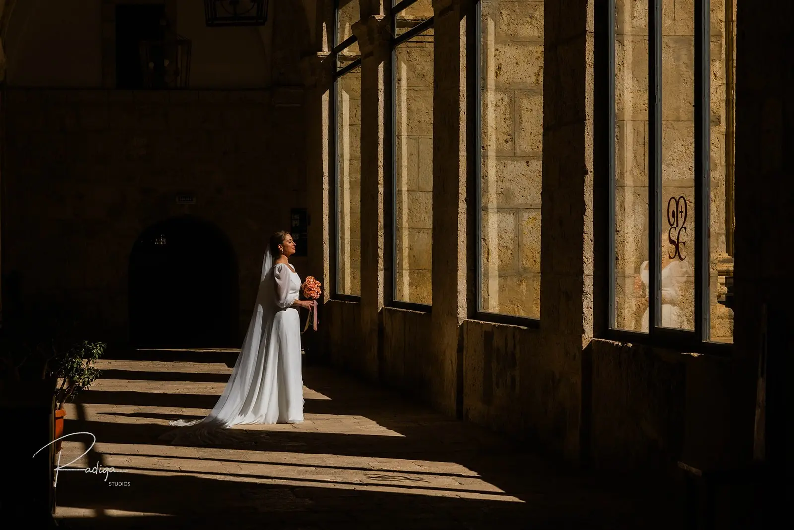 La novia en la galería del claustro, entre franjas de luz