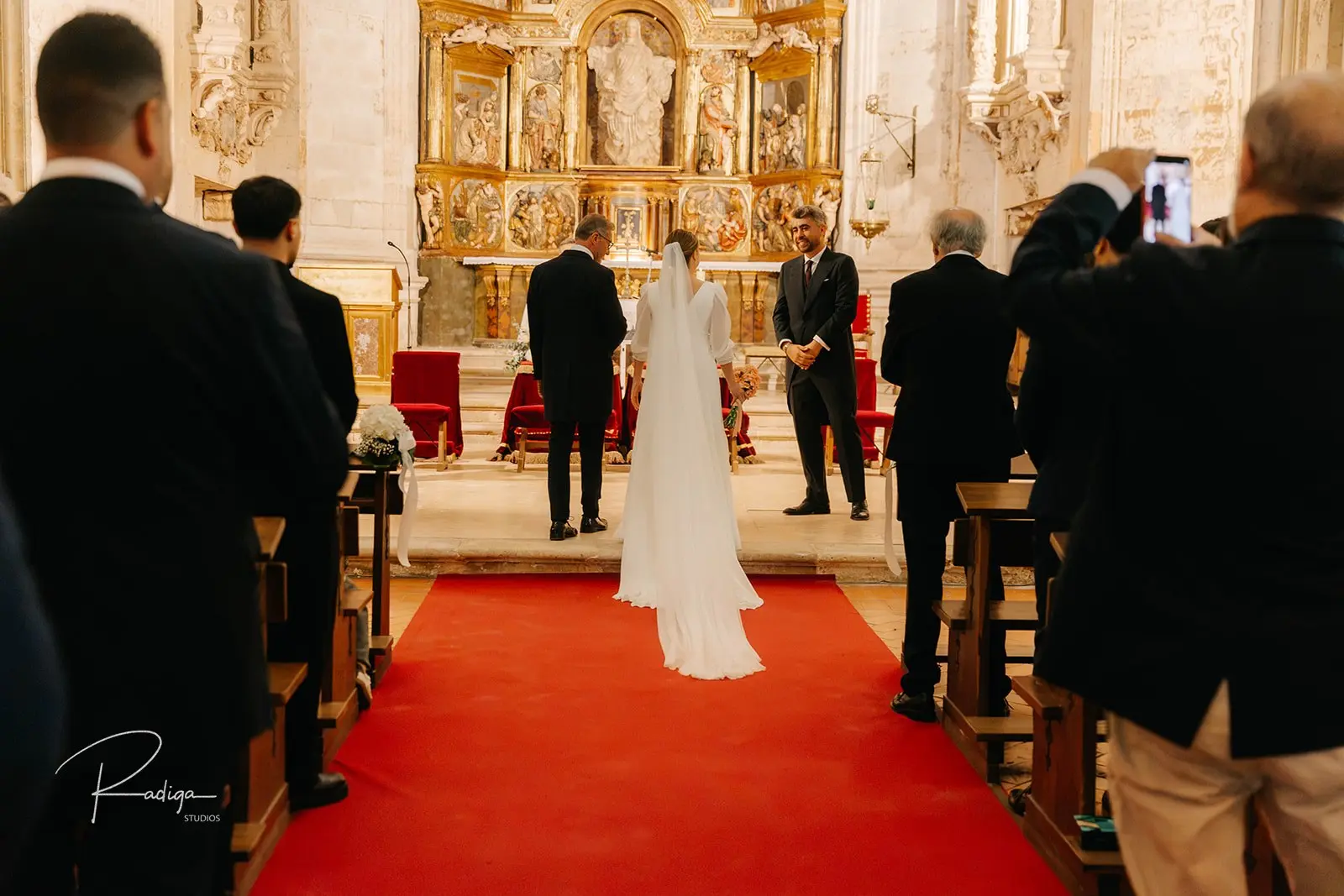 La novia avanza hacia el retablo por la alfombra roja de la iglesia