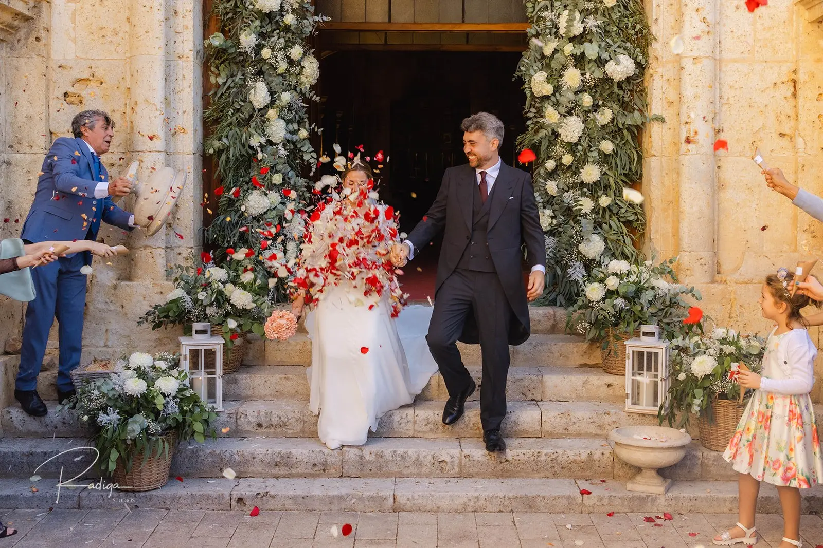 Los novios salen de la iglesia bajo una lluvia de pétalos rojos