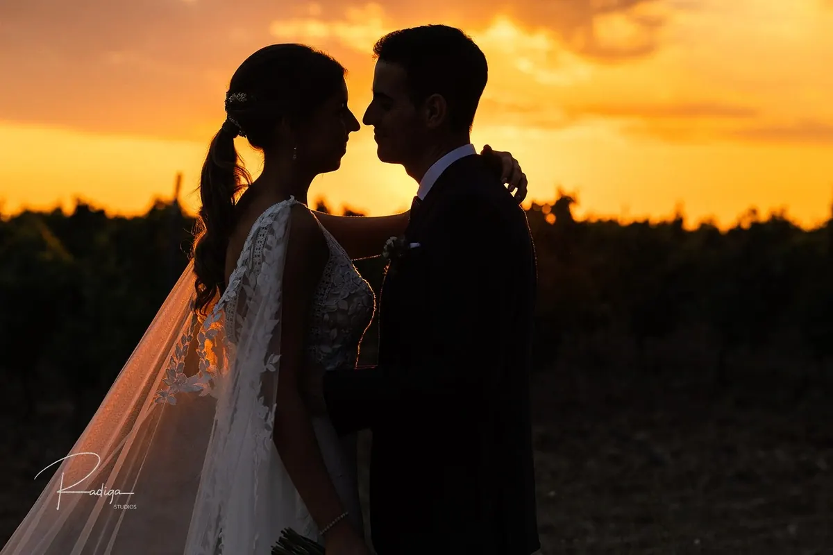 Los novios frente a frente a contraluz con la puesta de sol