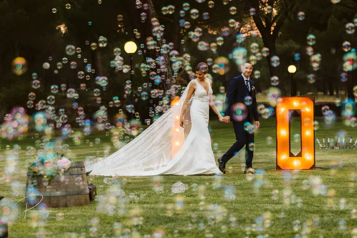 Los novios bajo una lluvia de pompas de jabón junto a las letras luminosas