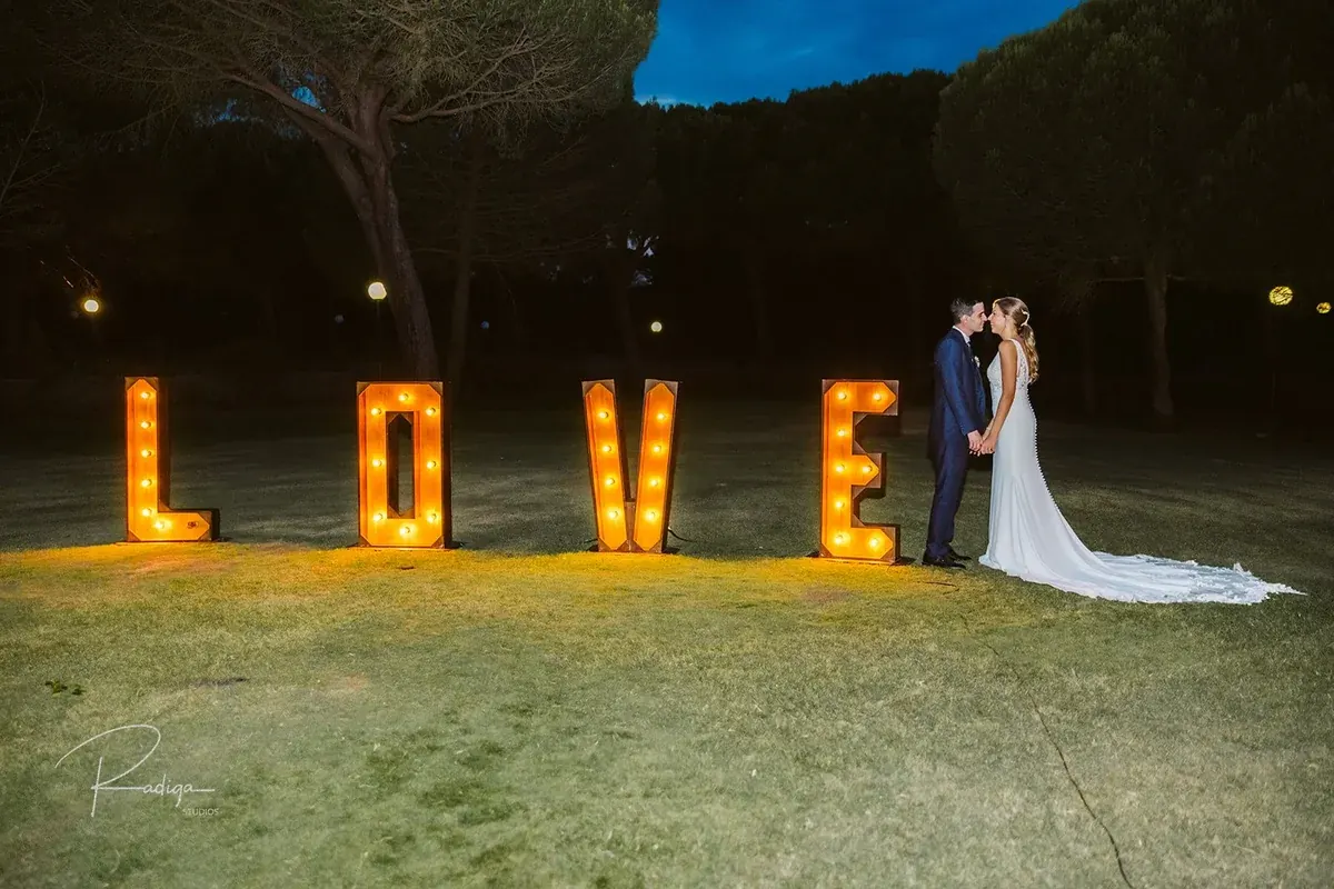Los novios junto a las letras LOVE iluminadas por la noche