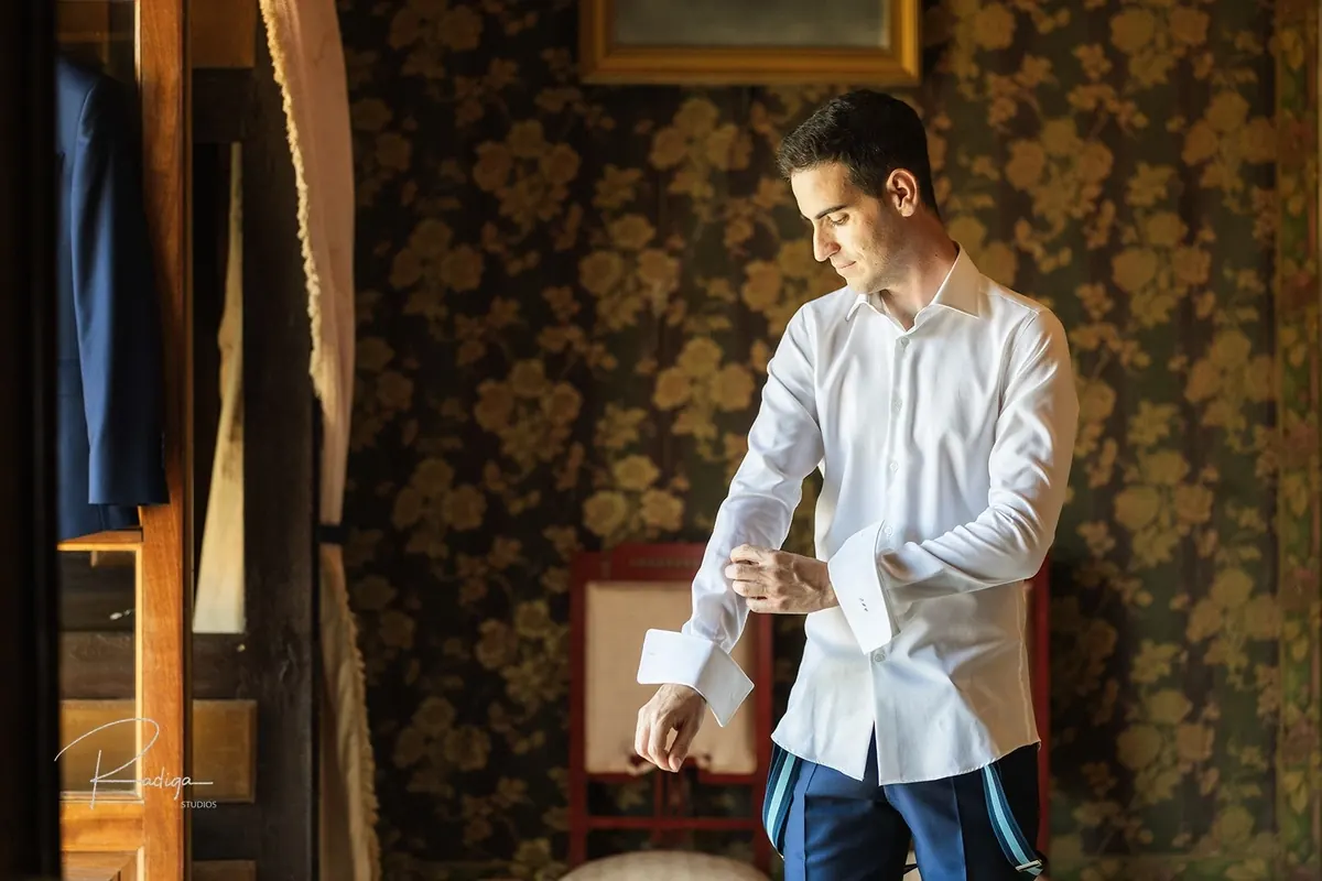 El novio se abrocha la camisa en la habitación
