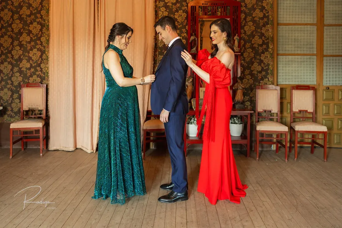 Dos invitadas ayudan al novio con la chaqueta