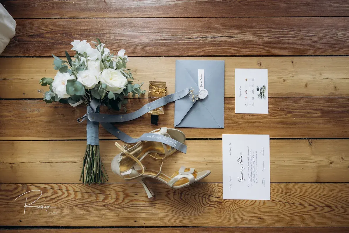 El ramo, los zapatos y las invitaciones de la boda sobre una mesa de madera