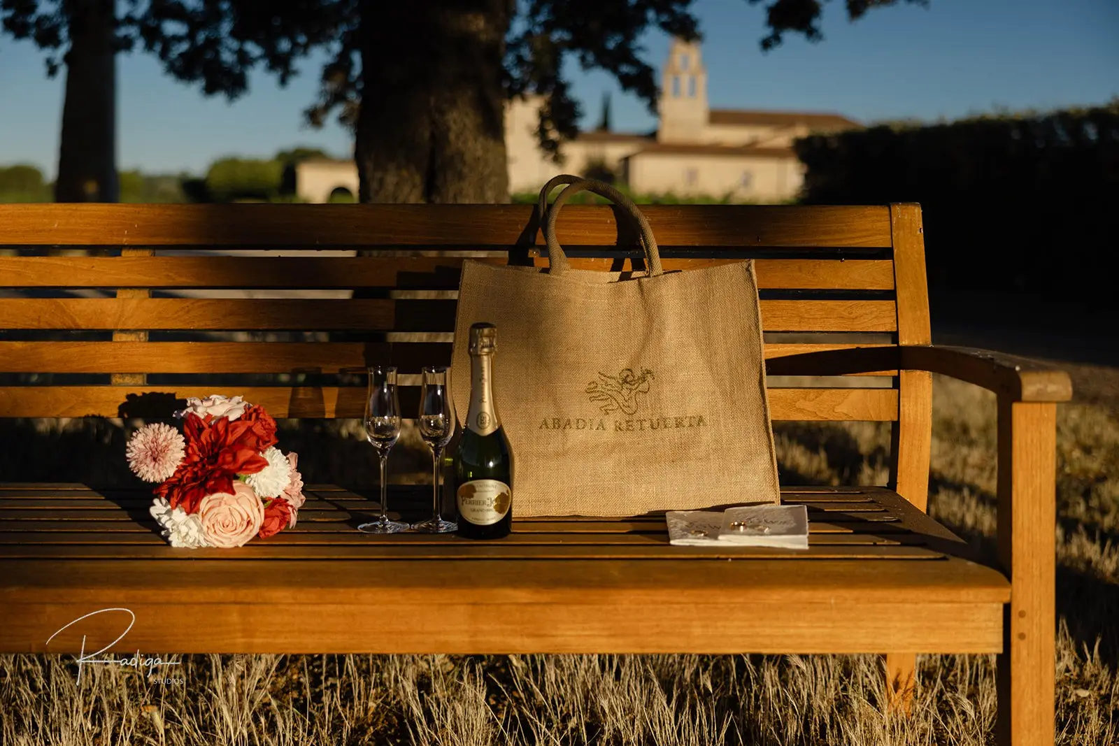 Bouquet, champagne and glasses on a wooden bench with the abbey behind