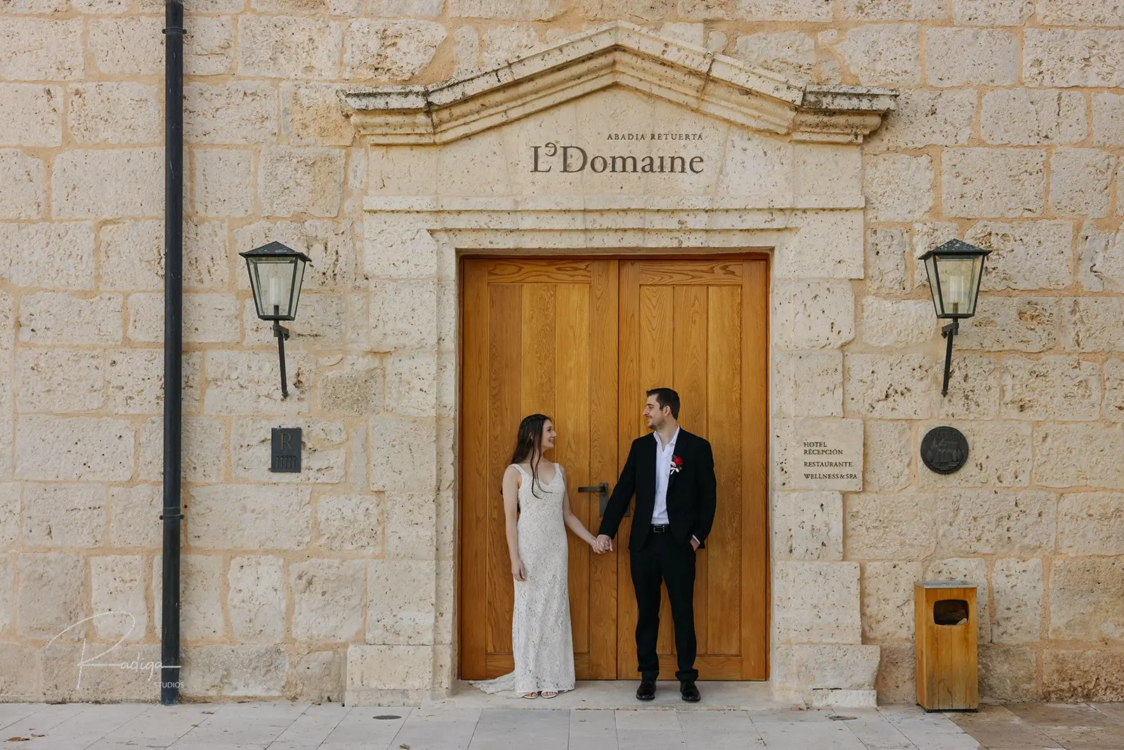 The couple at the stone façade and wooden door of Abadía Retuerta LeDomaine