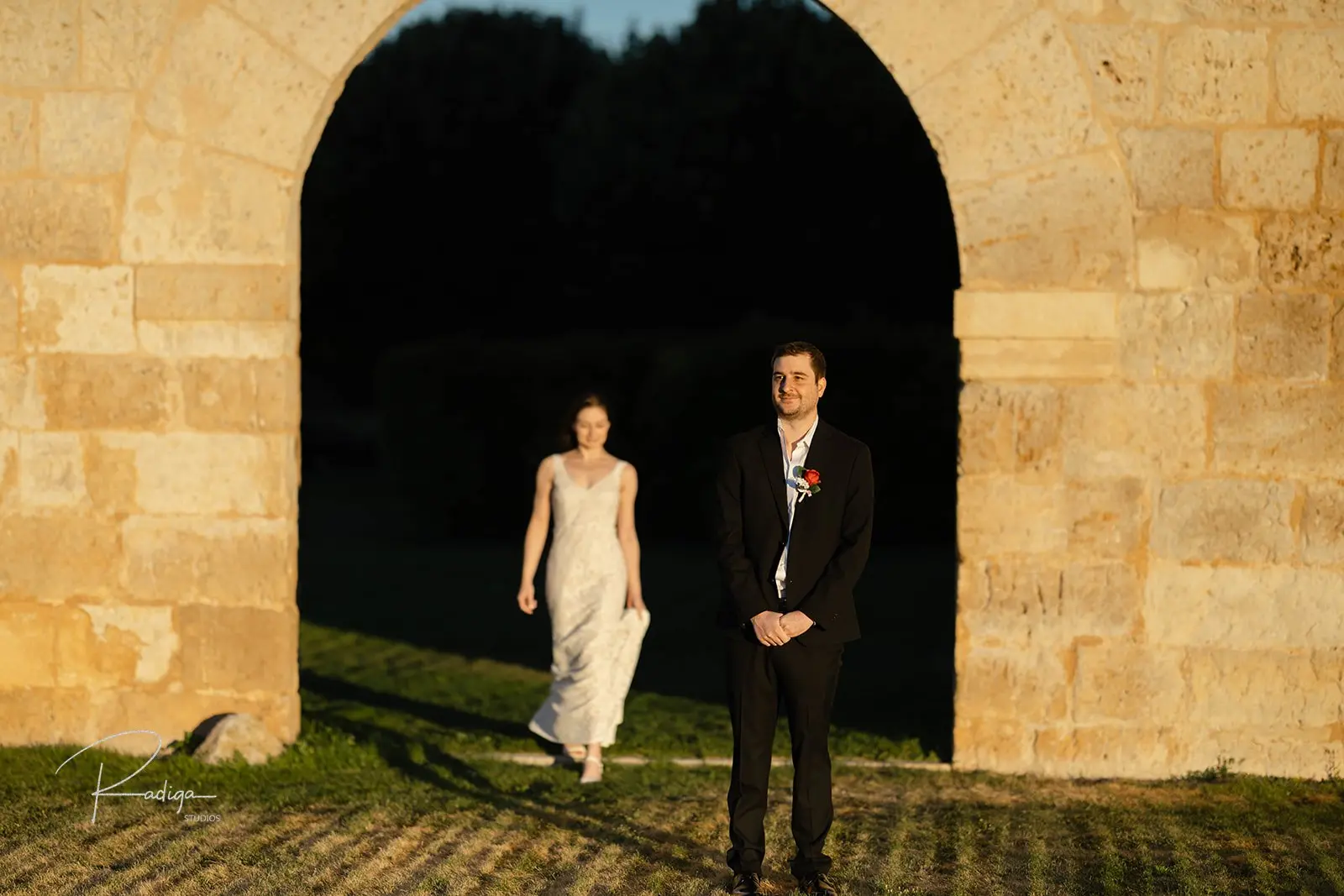 The couple under a stone arch in the abbey gardens