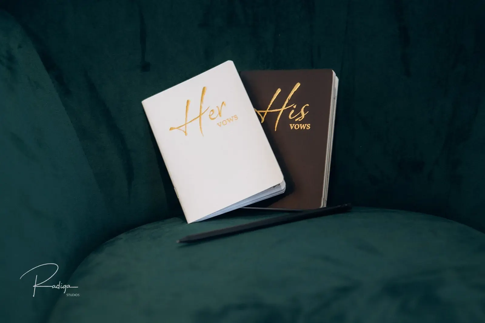 Her vows and his vows booklets on a green velvet chair