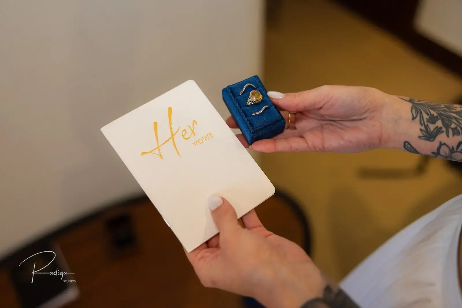 The groom holds the bride's vows booklet and the ring box