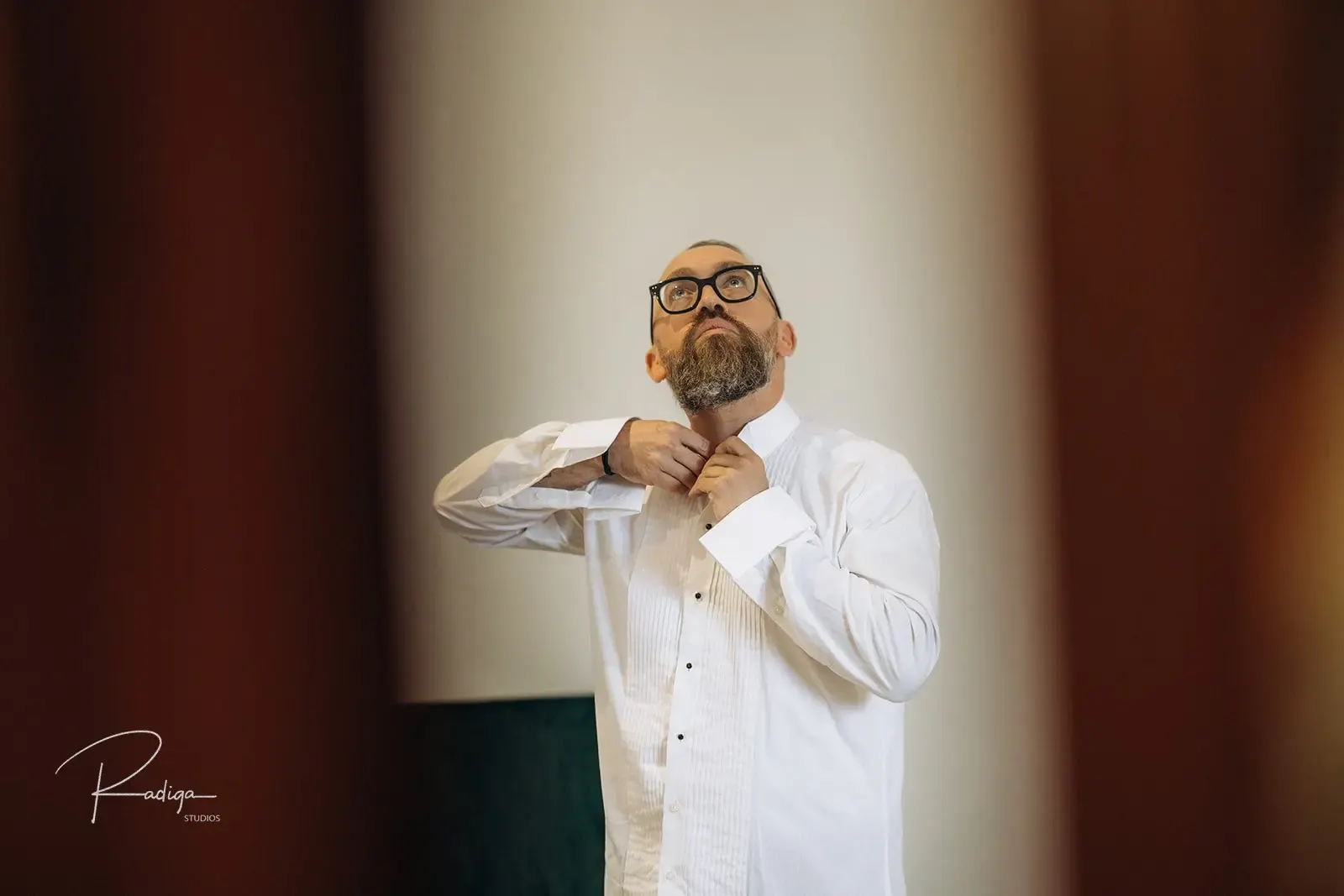 The groom fastening his bow tie while getting ready