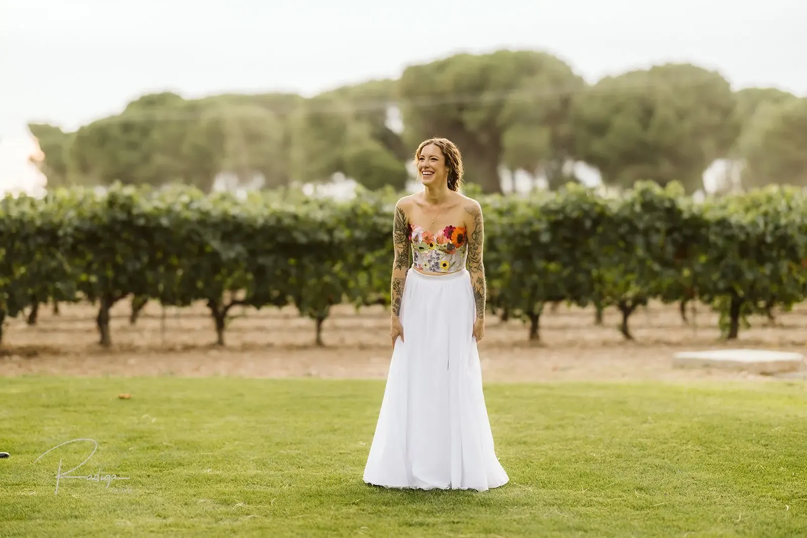 The bride twirls on the lawn in front of the vineyard