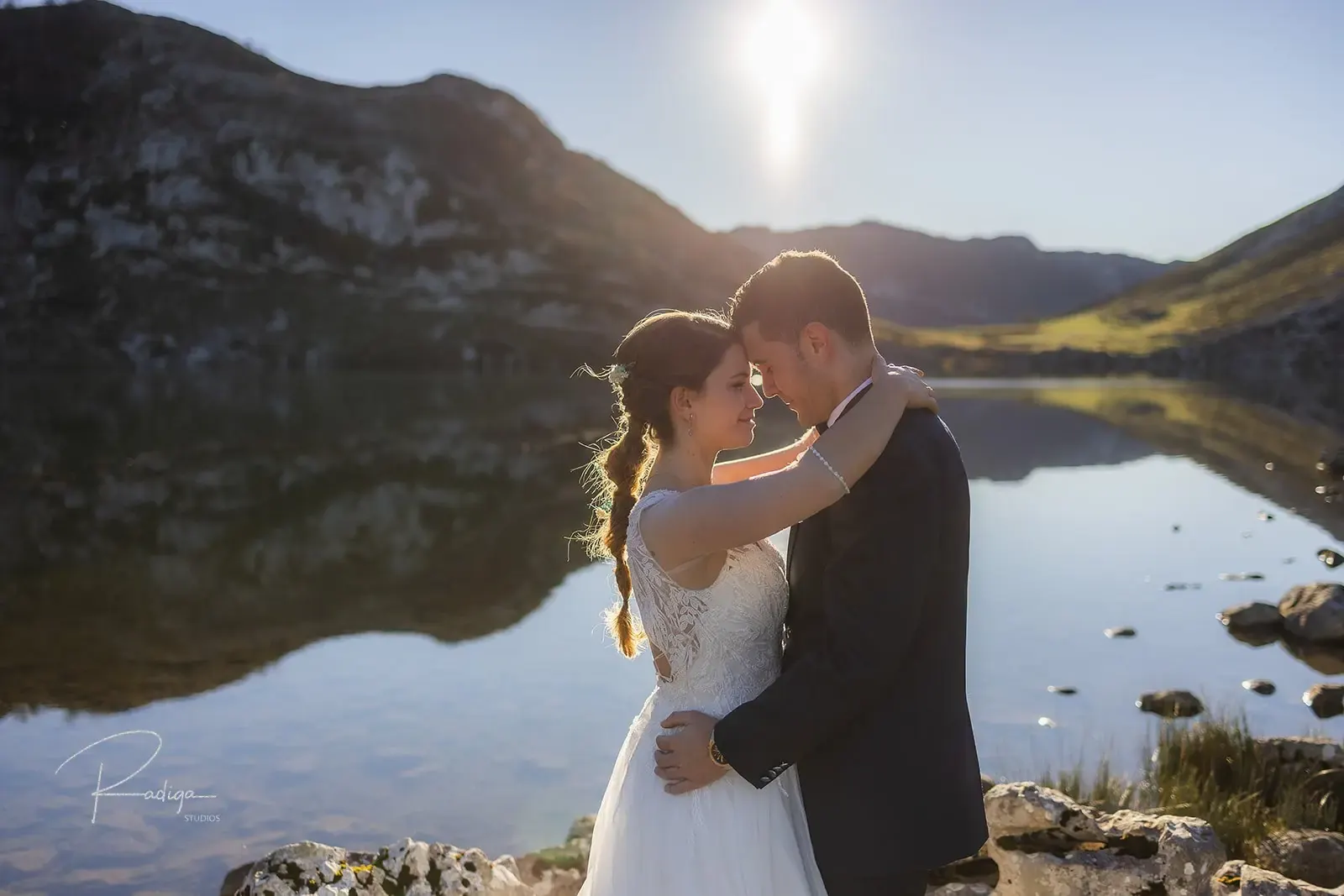 Los novios se besan a orillas de uno de los Lagos de Covadonga, con las montañas reflejadas en el agua