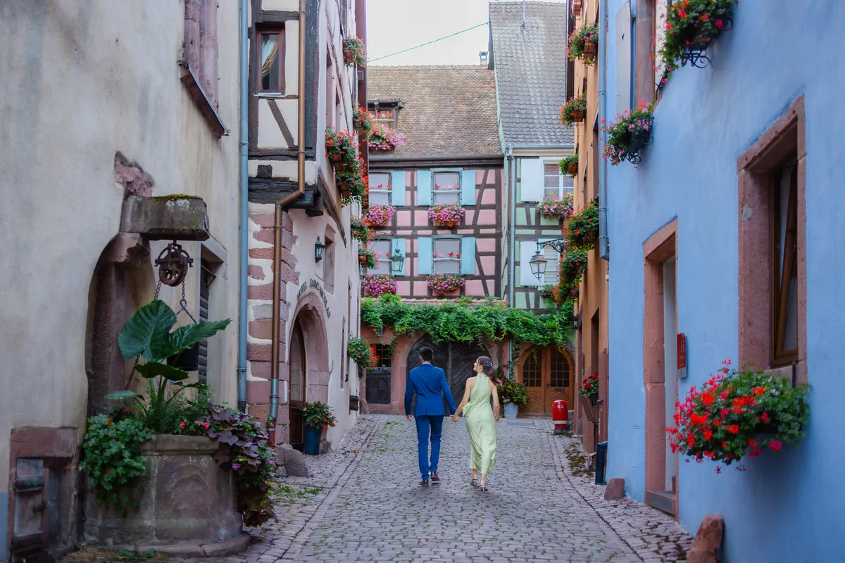 Víctor y Sandra en la preboda por un callejón de Riquewihr entre fachadas de colores y geranios