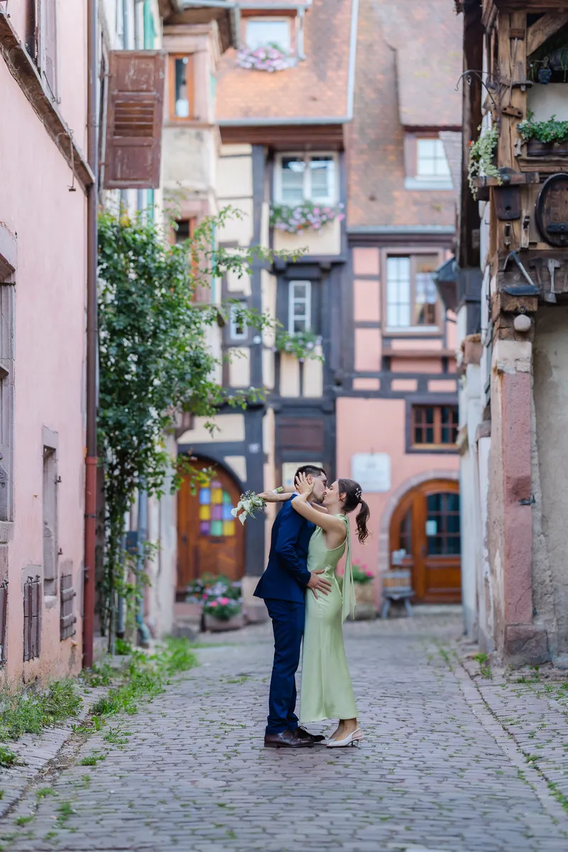 Beso en una calle empedrada de Riquewihr, entre casas de entramado de madera