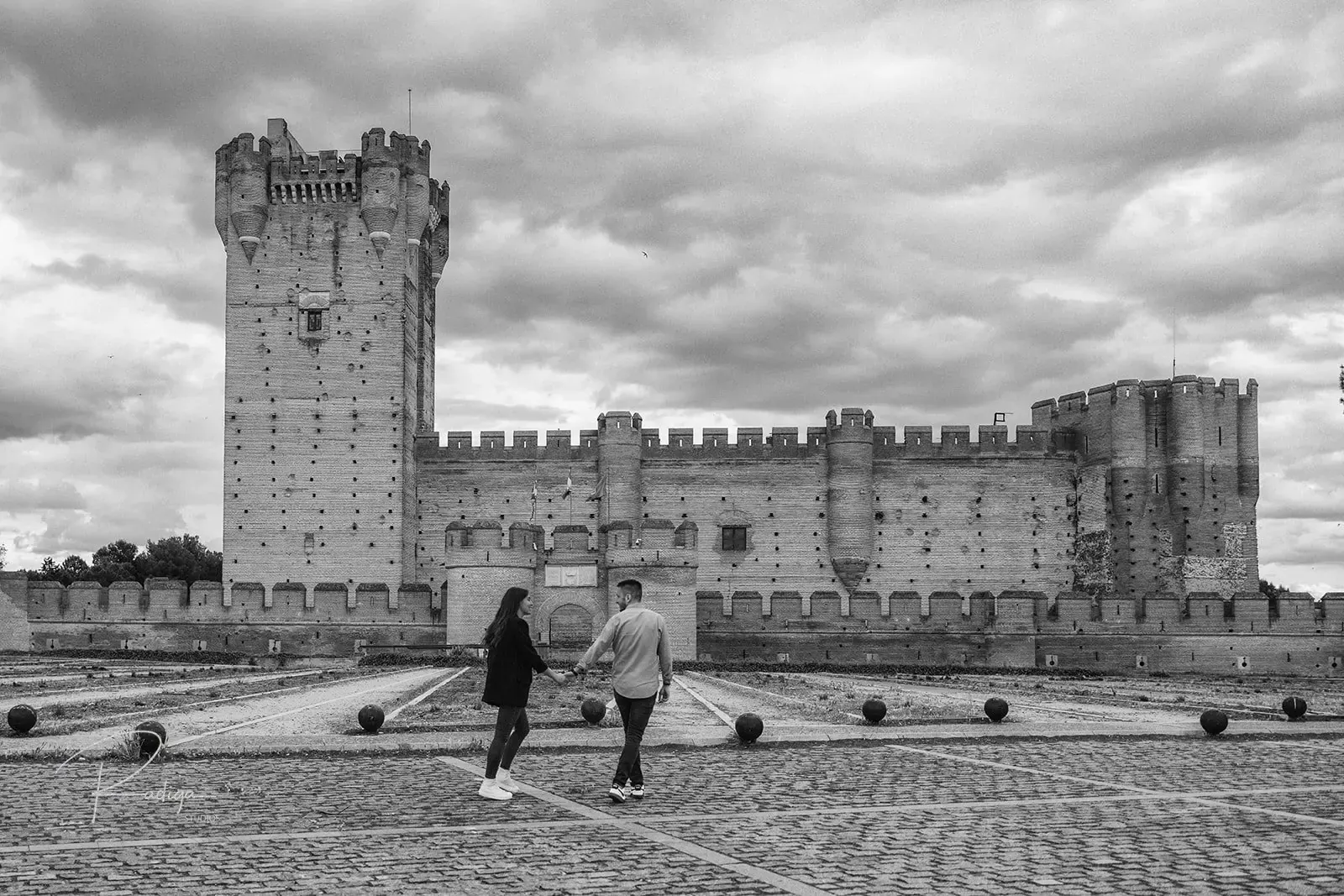 La pareja camina hacia el Castillo de la Mota de Medina del Campo, en blanco y negro